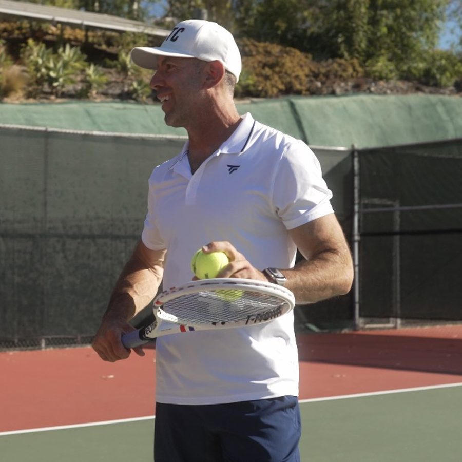 Tennis coach on court holding a racket and ball